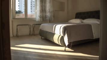 Un dormitorio con cama, ventana y vistas a edificios.