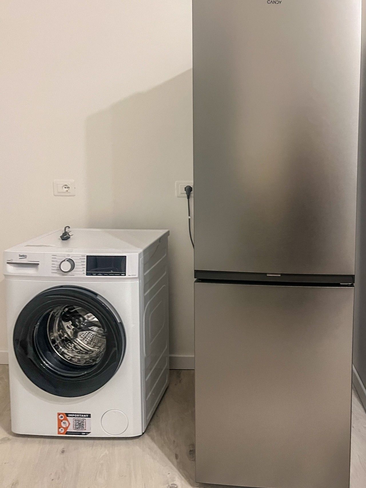 Une cuisine compacte équipée d’un lave-linge intégré et d’un réfrigérateur en acier inoxydable.
