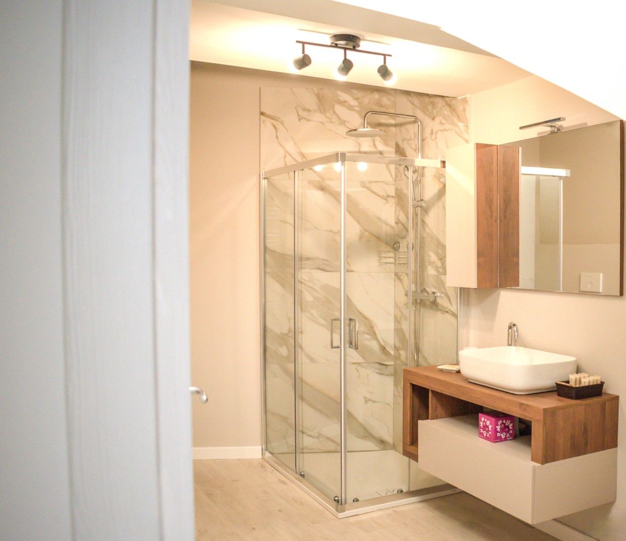 Une salle de bain moderne avec une douche à parois de verre, un meuble-lavabo en bois et un grand miroir.