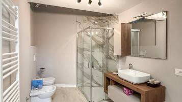 A modern bathroom with a glass shower enclosure, a white sink, and a vanity with a mirror.