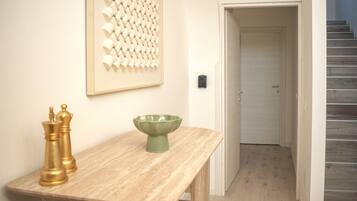 A room with a wooden table, two golden chess pieces, a green bowl, and a framed abstract art piece on the wall.