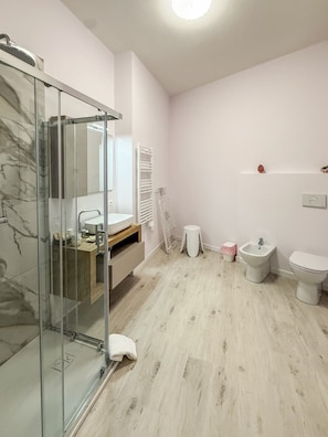 A modern bathroom with a glass shower enclosure, a sink, a bidet, and a toilet. - defaultName (Termoli)