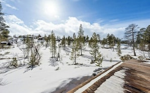 A snowy landscape with a wooden deck and a row of houses in the background. - A mountain cabin with board games and a pool table (Setesdalen)