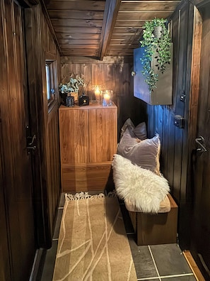 A cozy room with a wooden wardrobe, a bench with a fluffy pillow, a small table with candles, and a wall-mounted plant. - A mountain cabin with board games and a pool table (Setesdalen)