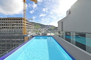 Une piscine sur le toit, d’où l’on peut admirer un chantier de construction et, au loin, une colline.