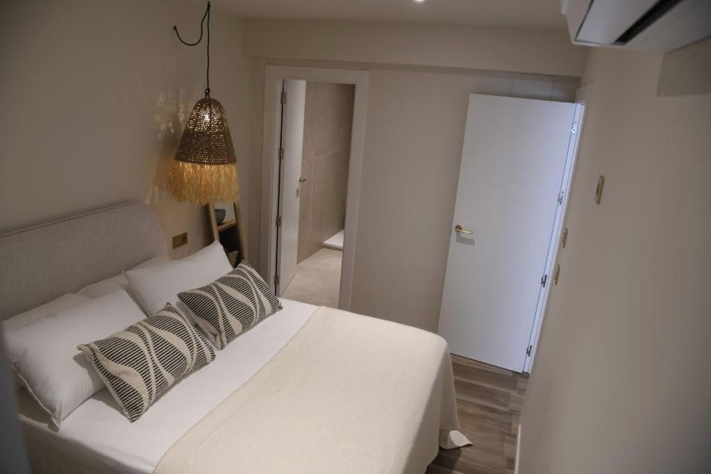 Ein Schlafzimmer mit Bett, einer Pendelleuchte, einer Tür und einem Flur.