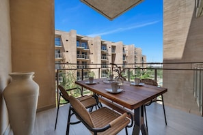 A balcony with a wooden table, chairs, and a vase. - Cabo Getaway · 2BR · Pool + Jacuzzi · Near Beach (Cabo San Lucas)