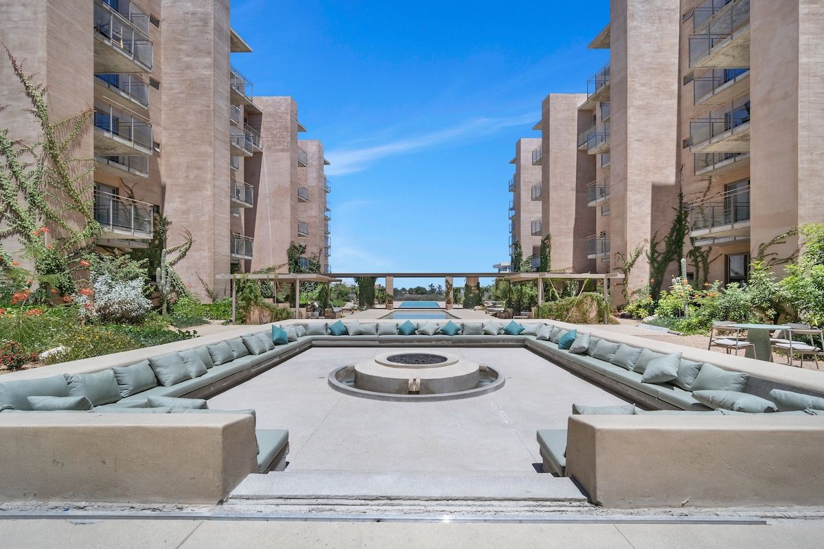 A courtyard with a central seating area, surrounded by high-rise buildings with balconies.
