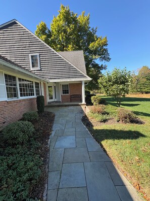 A residential house with a brick facade, a covered porch, and a stone pathway leading to the entrance. - Spacious 5-bedroom house in tranquil Princeton (Princeton)