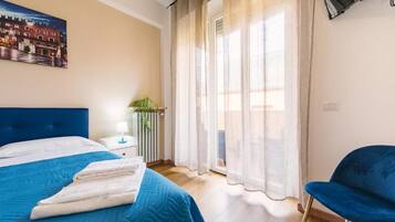 Une chambre d’hôtel avec un lit, une chaise, un radiateur, une fenêtre avec des rideaux et un tableau au mur.