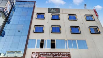 A building with multiple windows, some of which are boarded up. There is a sign for 'Dream Comforts Lodging & Boarding' with a bar attached.
