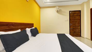 A hotel room with a large bed, a wooden door, and a ceiling fan.