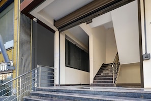 Una escalera que sube a un piso superior, con barandilla metálica y una puerta al final.