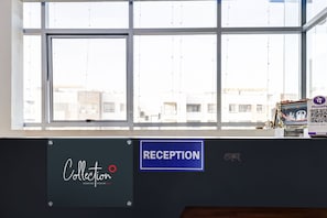 Zona de recepción con un amplio ventanal, un cartel que dice 'Collection' y un cartel que indica 'Reception'.