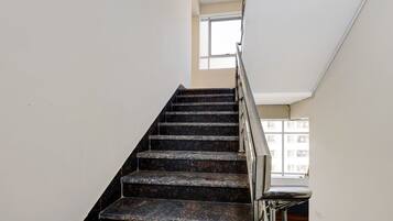 A staircase with dark marble steps and a metal handrail, leading to a landing with a window.