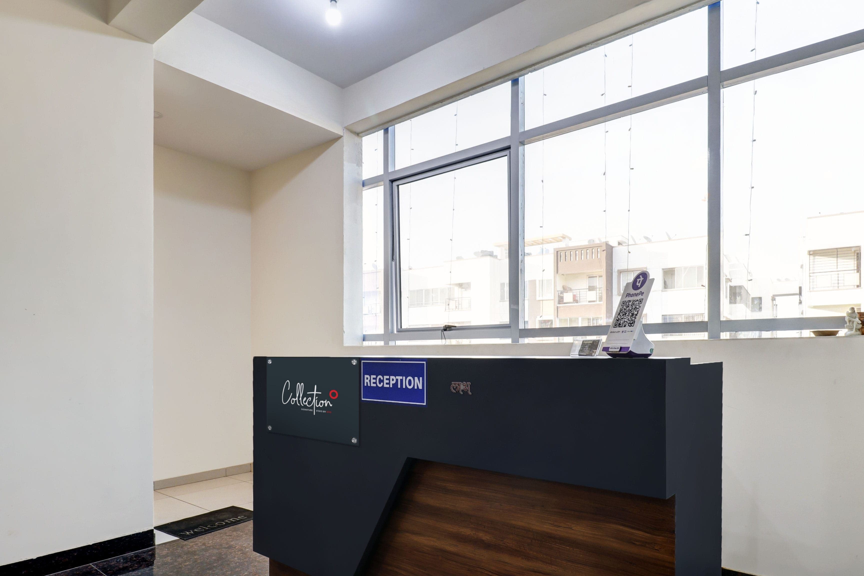 A reception desk with a 'RECEPTION' sign, a 'Collection' sign, and a QR code for PhonePe.