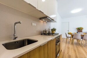 Eine moderne Küche mit einer Edelstahlspüle, einem Gasherd und Holzschränken.