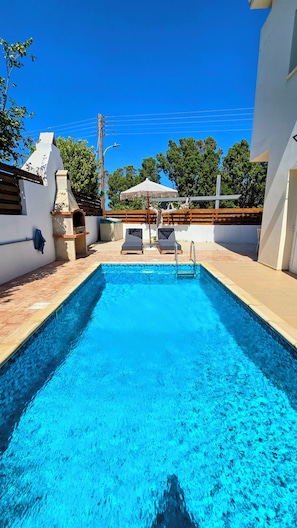 A swimming pool with two lounge chairs, a wooden deck, and a view of the sky. - Villa Alkioni 31 with Private Pool & Jacuzzi (Paralimni)