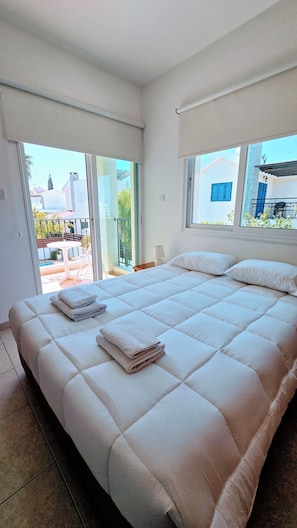 A bedroom with a large bed, a view of the outside, and a balcony. - Villa Alkioni 31 with Private Pool & Jacuzzi (Paralimni)