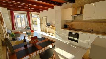 Una cucina moderna con mobili bianchi, un piano di lavoro in legno e un forno integrato.