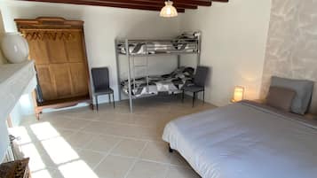 Un dormitorio con literas, un escritorio, una silla, un armario y una lámpara de noche.