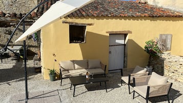 Een terras met tuinmeubilair, een witte parasol en een stenen muur.
