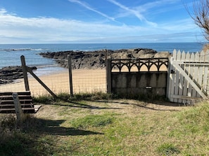 A beach entrance with a wooden gate, a fence, and a rocky shoreline. - Beachfront studio in a gated community, direct beach access, private parking (La Turballe)
