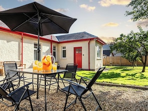 An outdoor patio with a table, chairs, and a large umbrella. - Fereneze (Isle of Arran)