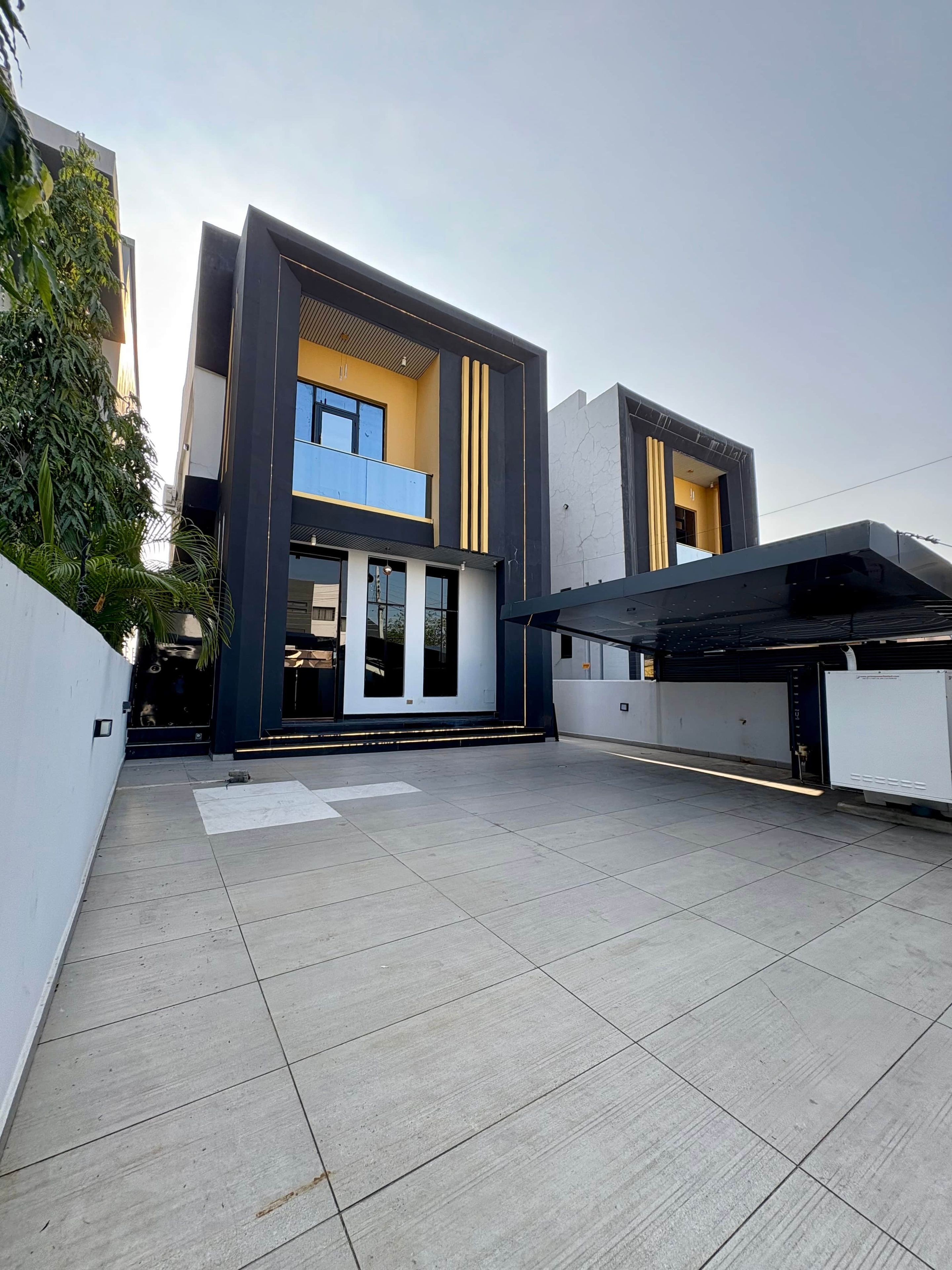 A modern two-story house with a flat roof, large windows, and a covered patio area.
