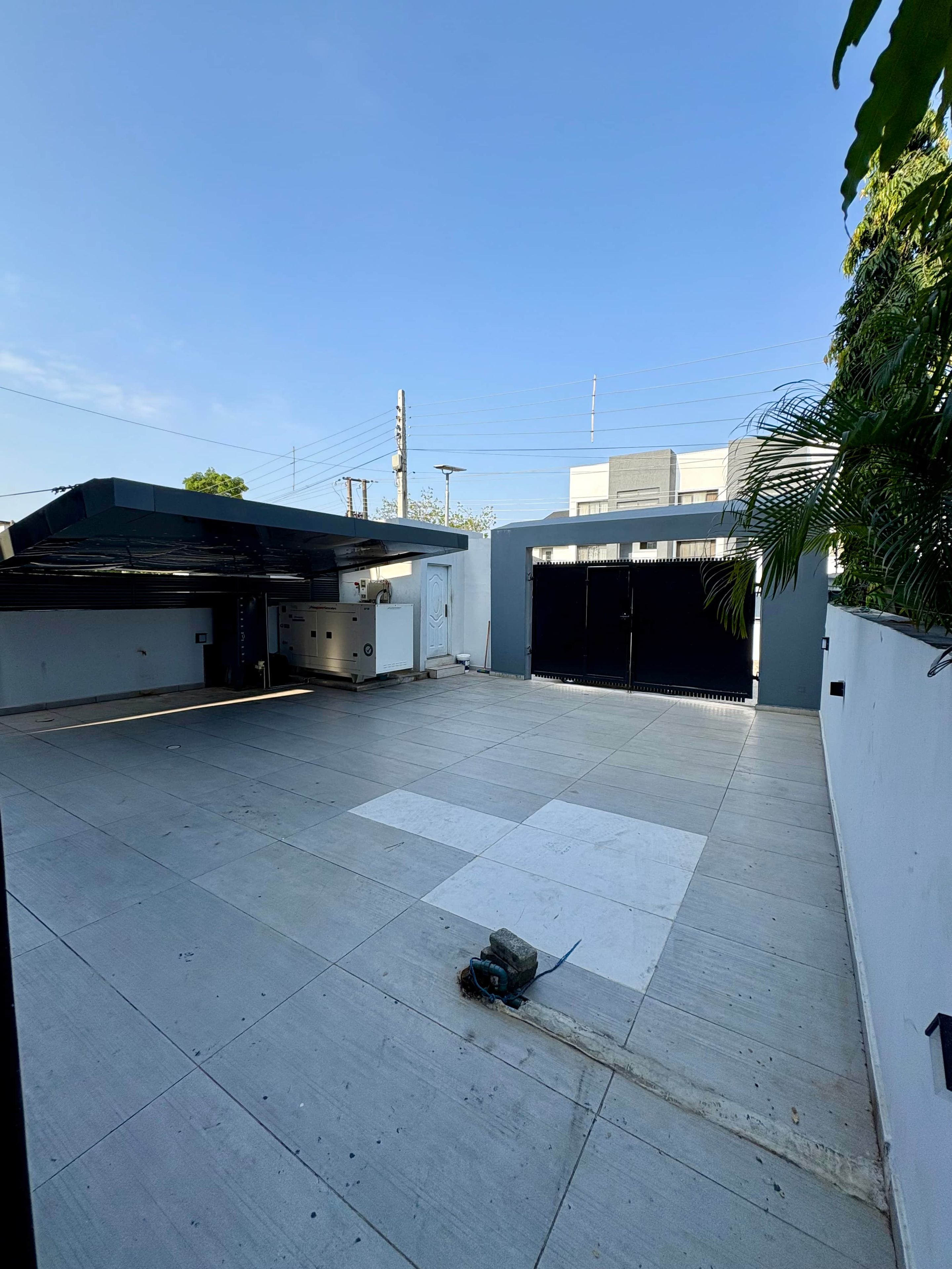A spacious outdoor area with a flat roof, a covered garage, and a gated entrance.