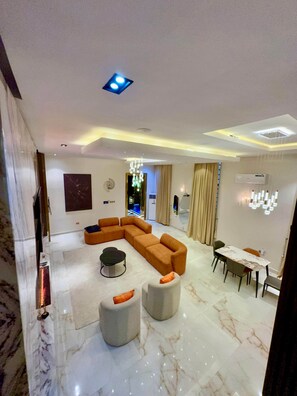 A modern living room with a sectional sofa, a dining table, and a chandelier.