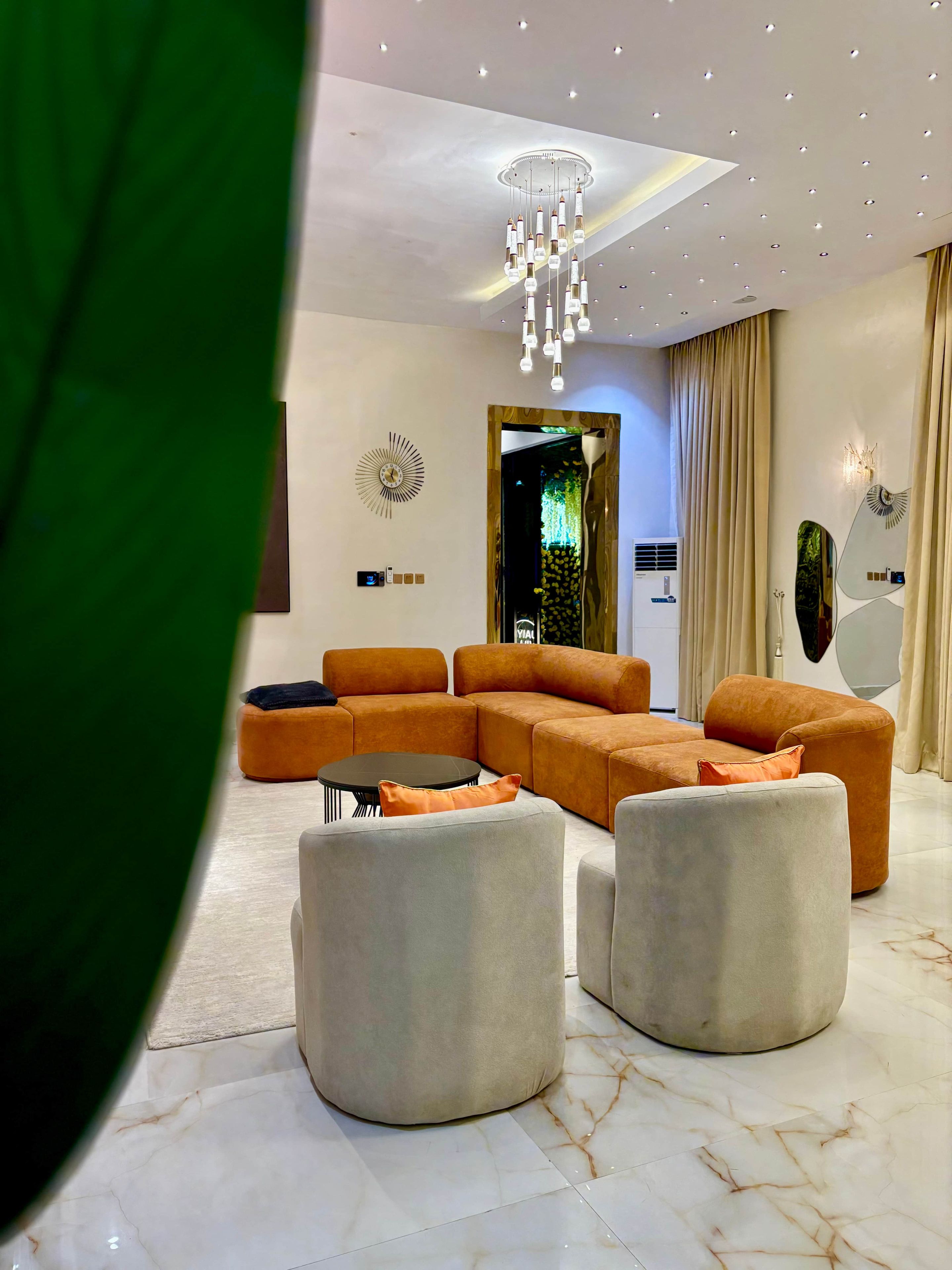 A modern living room with a sectional sofa, ottomans, a coffee table, and a chandelier.