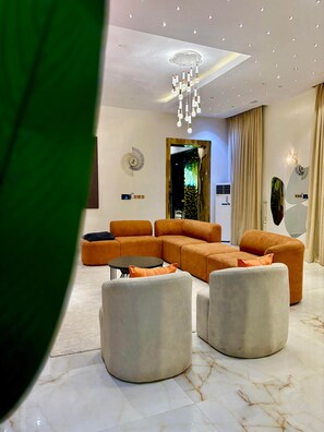 A modern living room with a sectional sofa, ottomans, a coffee table, and a chandelier.