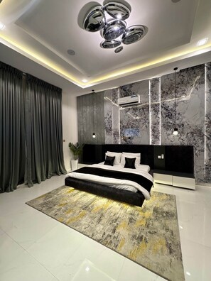 A modern bedroom with a large bed, a marble wall, and a ceiling light fixture.