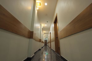 A long, narrow hotel corridor with wooden paneling on the walls and a polished floor. - Hotel Shri Ram (Agra)