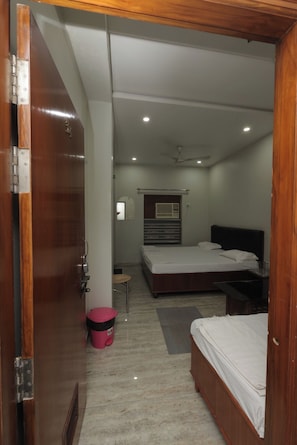 Un dormitorio con dos camas, ventilador de techo y ventana con persianas.