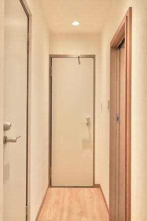 A hallway with a wooden floor, a closed door with a handle, and a light fixture on the ceiling. - A 6-minute walk from Shinjuku-Shin-Okubo Station! 4-Bedroom, 3-Story House for Exclusive Rental (Sleeps Up to 8) | 15-Minute Walk from Kabukicho (東京都新宿区大久保二丁目)