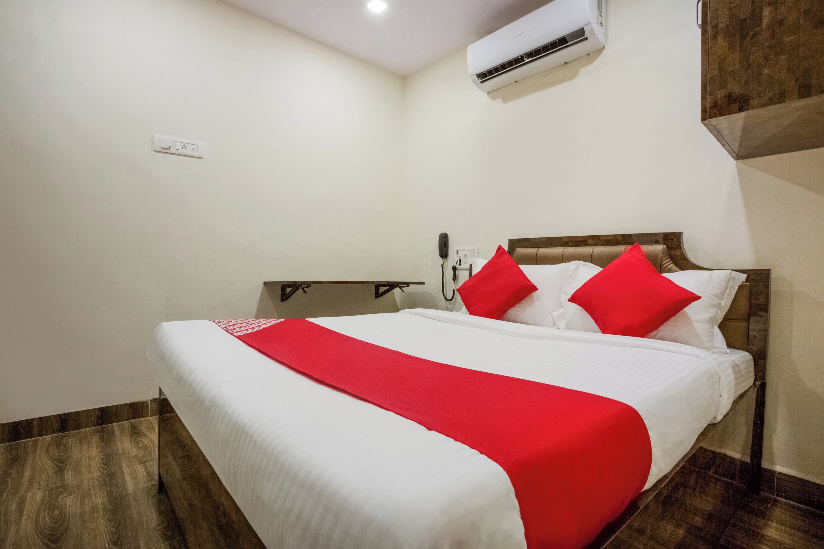 Una habitación de hotel con una cama, una mesita de noche, un teléfono y un equipo de aire acondicionado.