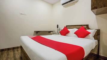 Una habitación de hotel con una cama, una mesita de noche, un teléfono y un equipo de aire acondicionado.