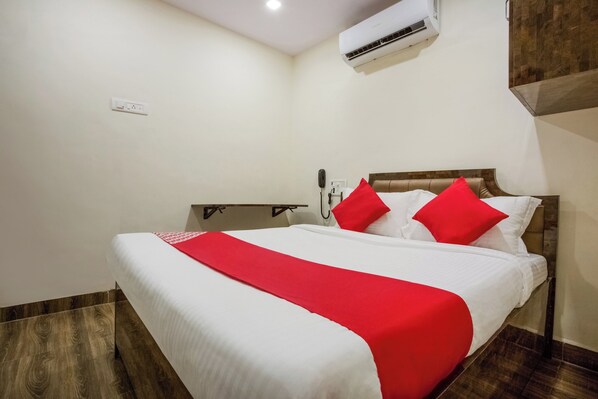 Una habitación de hotel con una cama, una mesita de noche, un teléfono y un equipo de aire acondicionado.