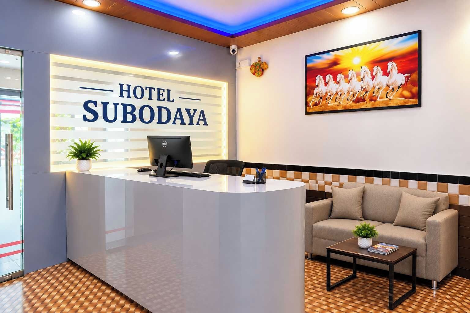 A hotel reception area with a reception desk, a computer, a sofa, and a painting of horses.