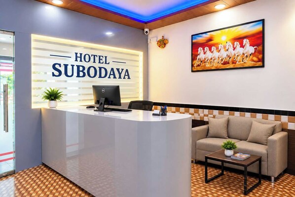 A hotel reception area with a reception desk, a computer, a sofa, and a painting of horses. - Collection O Sector 1 Navi Mumbai (Navi Mumbai)