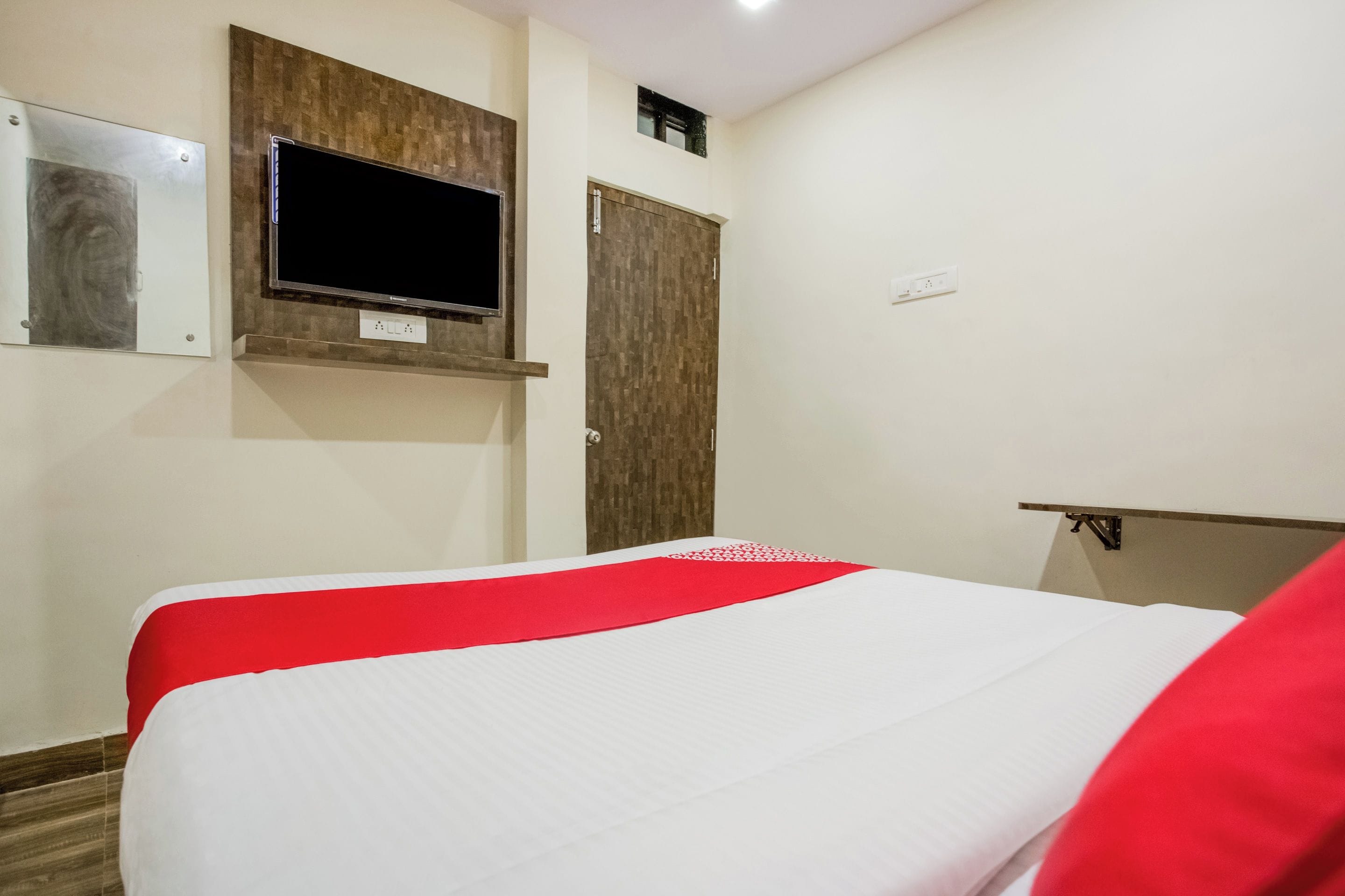 Ein Hotelzimmer mit einem Bett, einem an der Wand befestigten Fernseher und einer Tür.