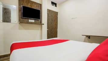Quarto de hotel com cama, televisão na parede e uma porta.