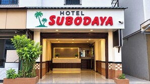 Entrada de un hotel con mostrador de recepción, logotipo de palmera y un letrero que dice 'HOTEL SUBODAYA'.