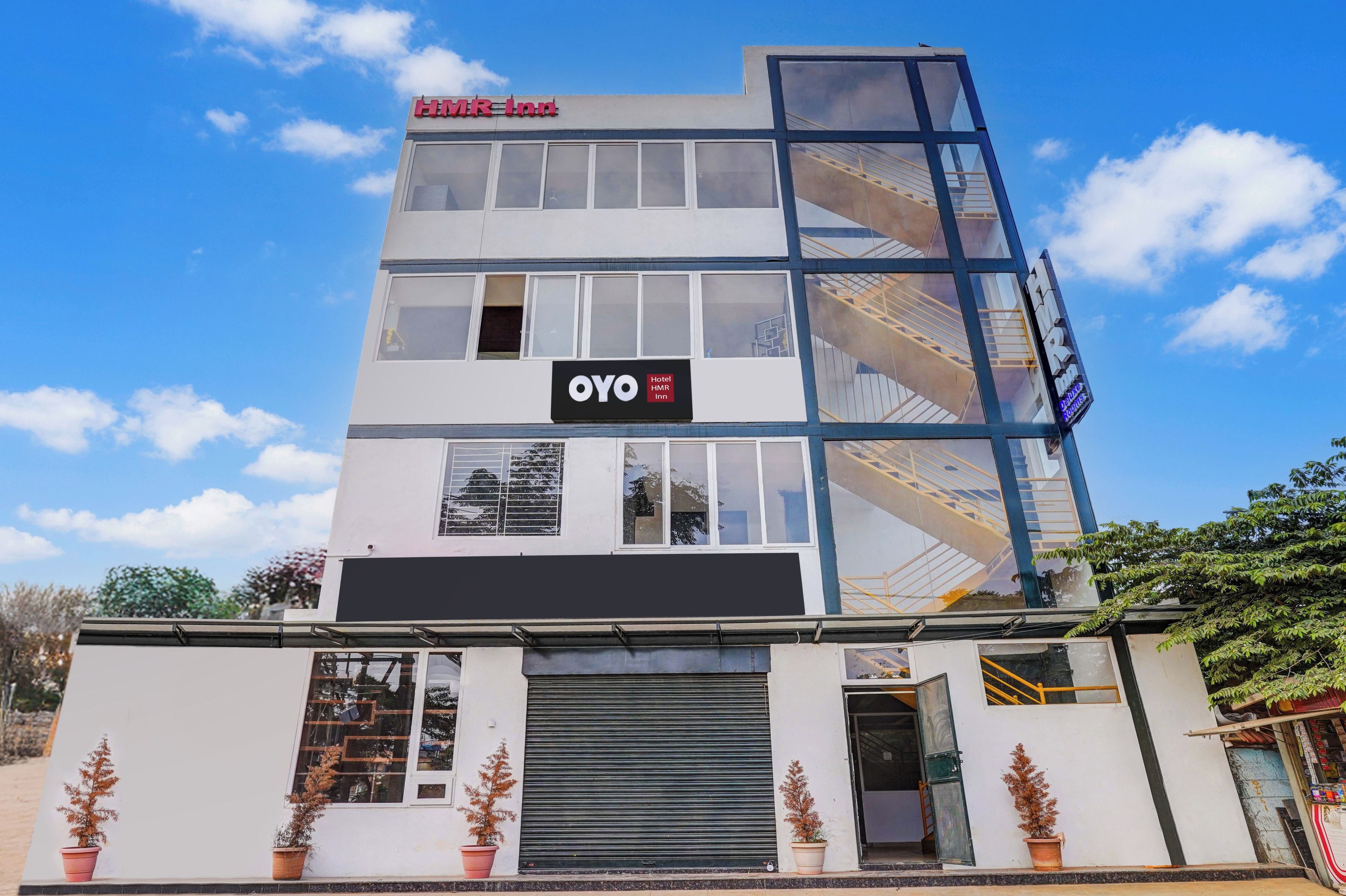 A modern hotel building with a glass facade, multiple windows, and a sign indicating it is part of the OYO hotel chain.