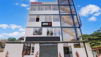 A modern hotel building with a glass facade, multiple windows, and a sign indicating it is part of the OYO hotel chain.