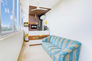 A reception area with a sofa, a clock, and a sign that reads 'OYO'. - Hotel O HMR Inn (Bangalore)