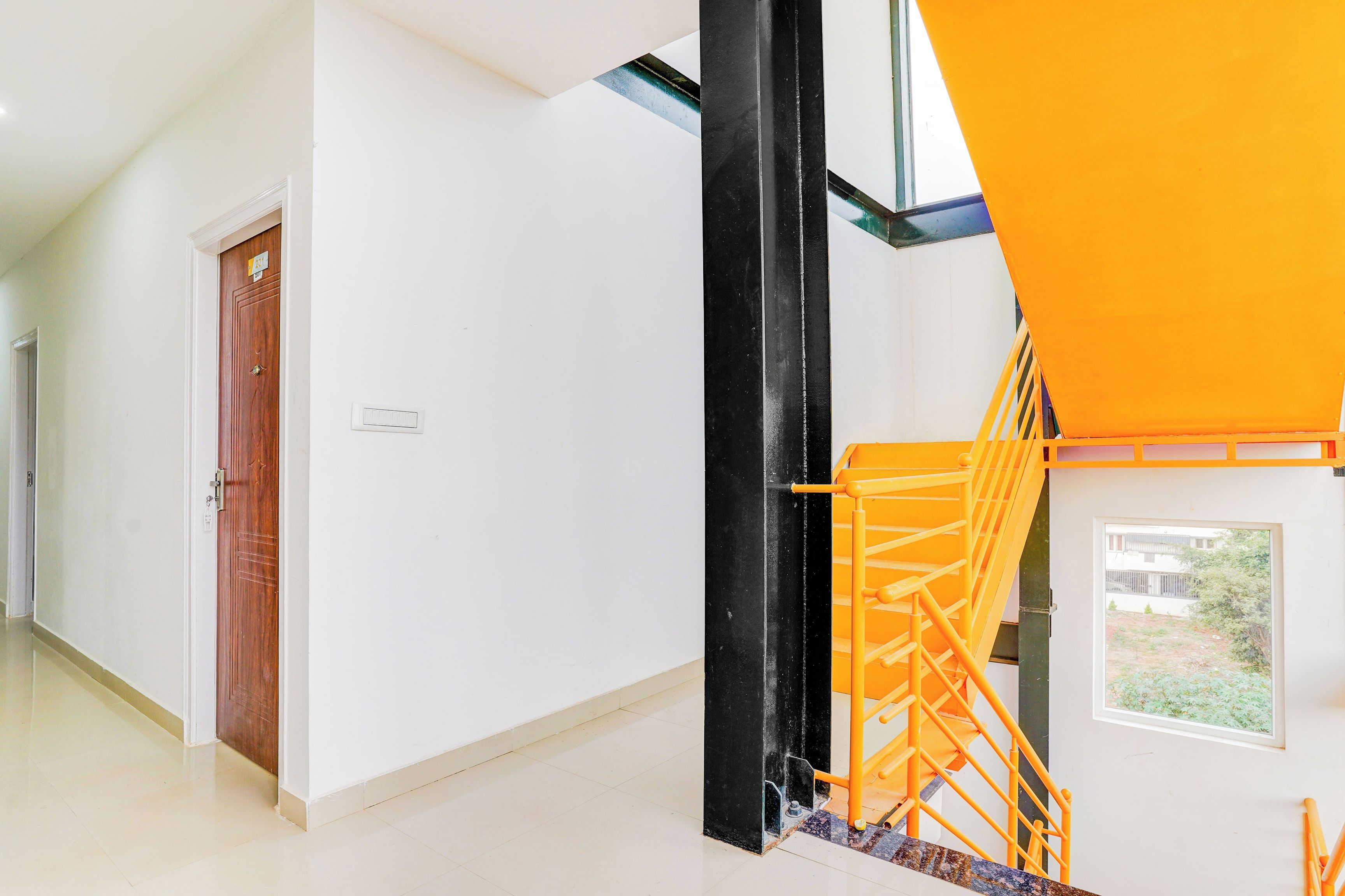 Un interior moderno con una escalera, una puerta de madera y una ventana con vistas.