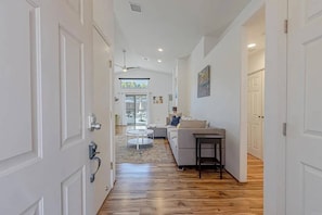 A hallway with a wooden floor leading to a living area with a sofa and a table. - La Quinta Cove Oasis | Private Pool & Mountain Views (La Quinta)